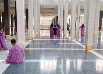 Antara pelancong yang memakai jubah masuk ke Masjid Negara. Foto dari Harian Metro