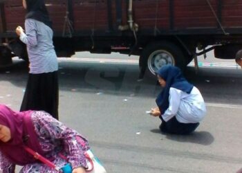 Beberapa individu cuba mengutip cebisan dipercayai Al-Quran yang bertaburan di atas jalan. Foto -Sinar Harian