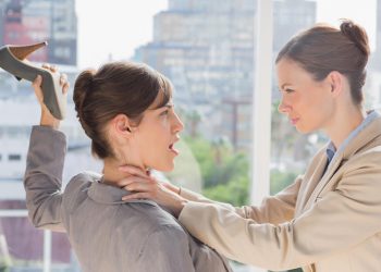 Businesswoman defending herself from her co worker strangling her in a bright office