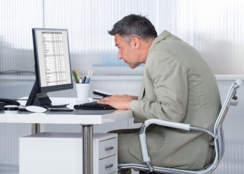 Side view of concentrated businessman using computer at desk in office